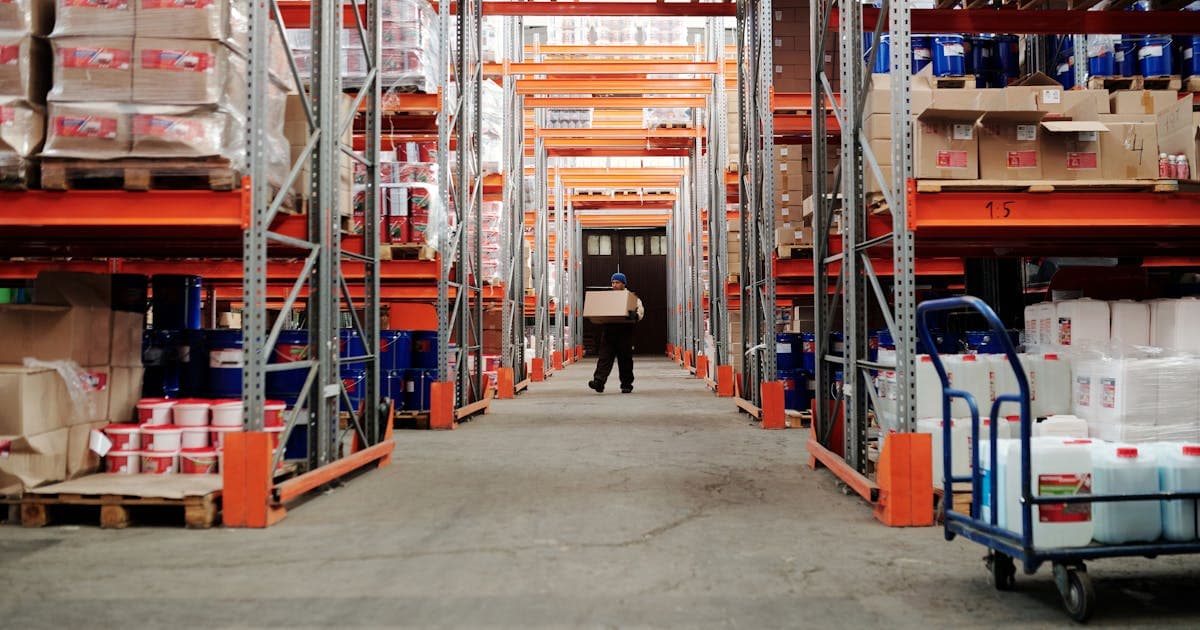 Warehouse worker scanning packages at a 3PL fulfillment center with quality control checkpoint visible